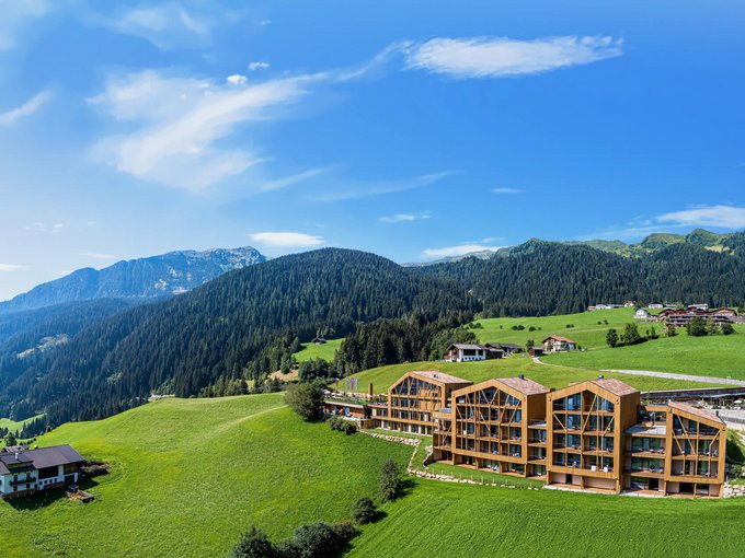 Nachhaltiger Urlaub Berglandschaft mit grünen Wiesen, Häusern und blauem Himmel