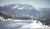 Zwei Skifahrer stehen auf schneebedecktem Berg mit Alpen im Hintergrund