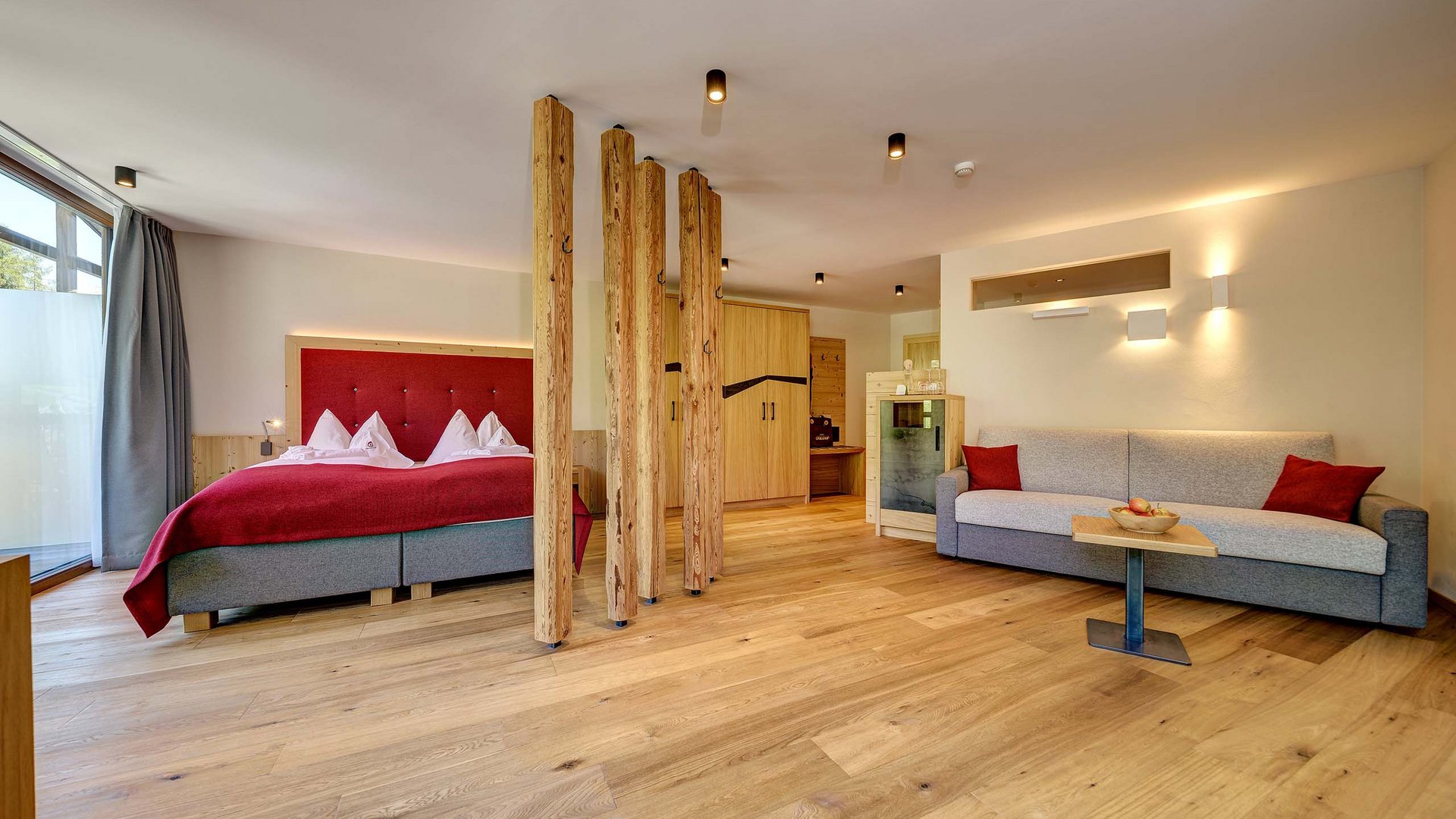 Inclusive services Modern hotel room with wooden floor, double bed, and sofa