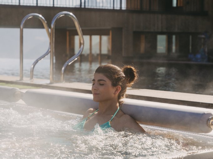 Ankommen, auspacken, abschalten in unserer Wellnesswelt Frau entspannt in einem Whirlpool mit dampfendem Wasser