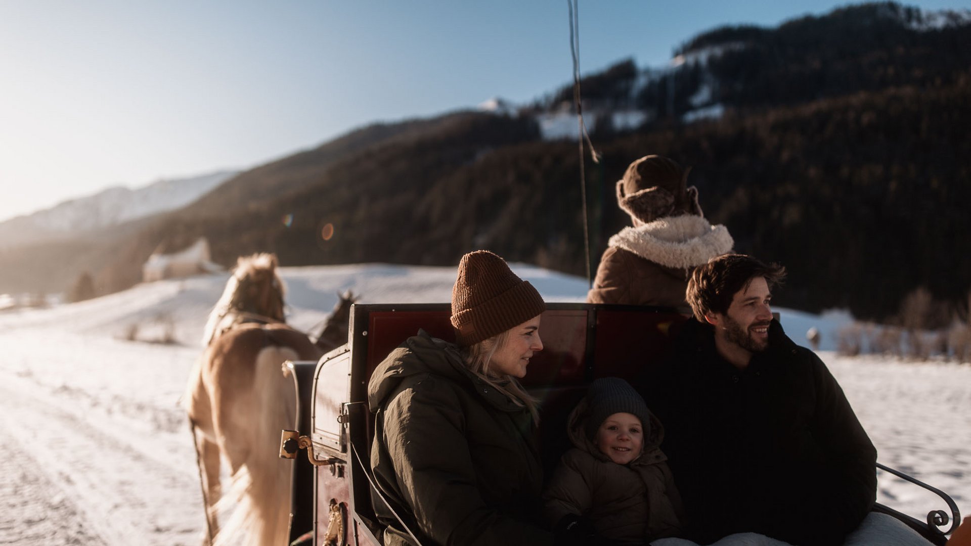 Aktivitäten mit Kindern im Ridnauntal Familie fährt im Pferdeschlitten durch eine verschneite Berglandschaft