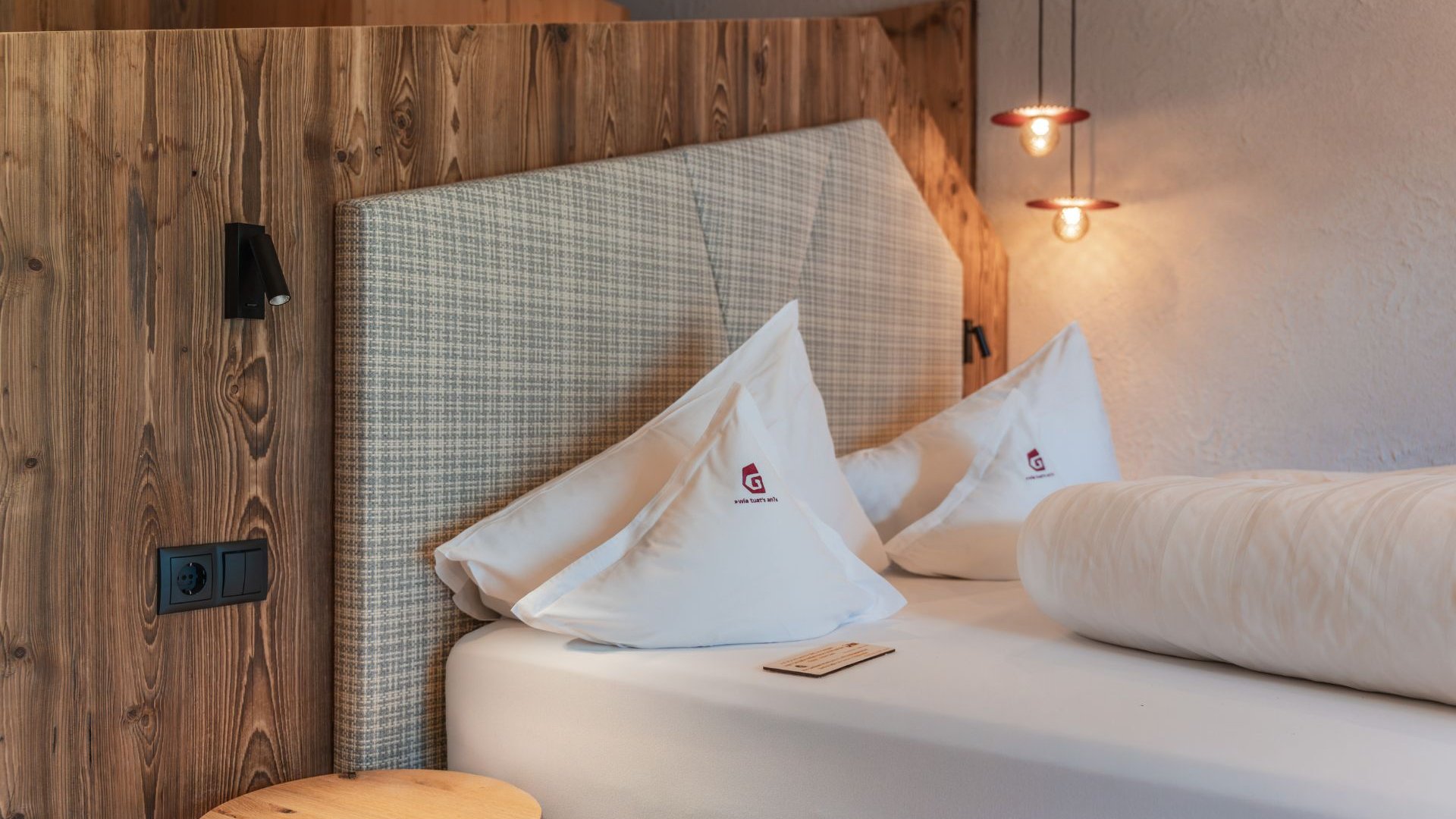 Servizi inclusi Accogliente camera d’hotel con parete in legno, letto imbottito e cuscini bianchi