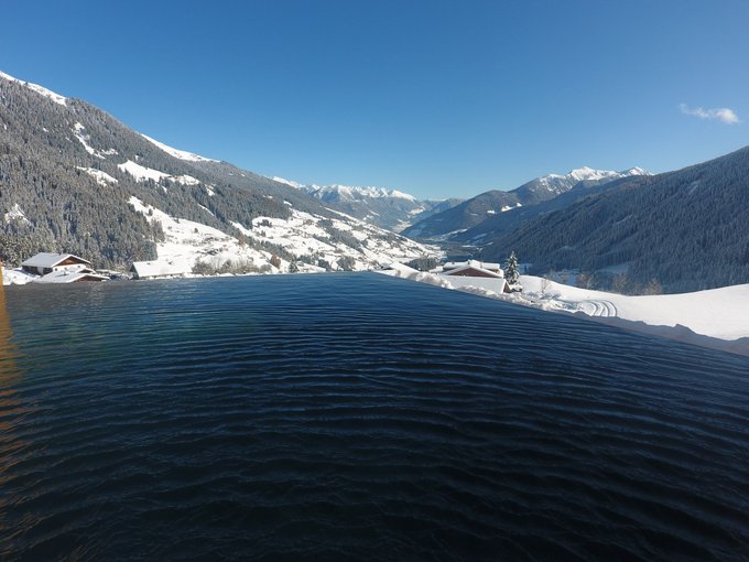 La Val Ridanna Piscina a sfioro con vista su montagne innevate e valle sotto cielo limpido