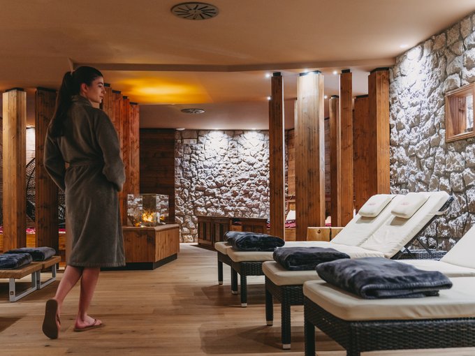 Day Spa Frau im Bademantel in einem modernen Spa mit Liegen und Steinwänden