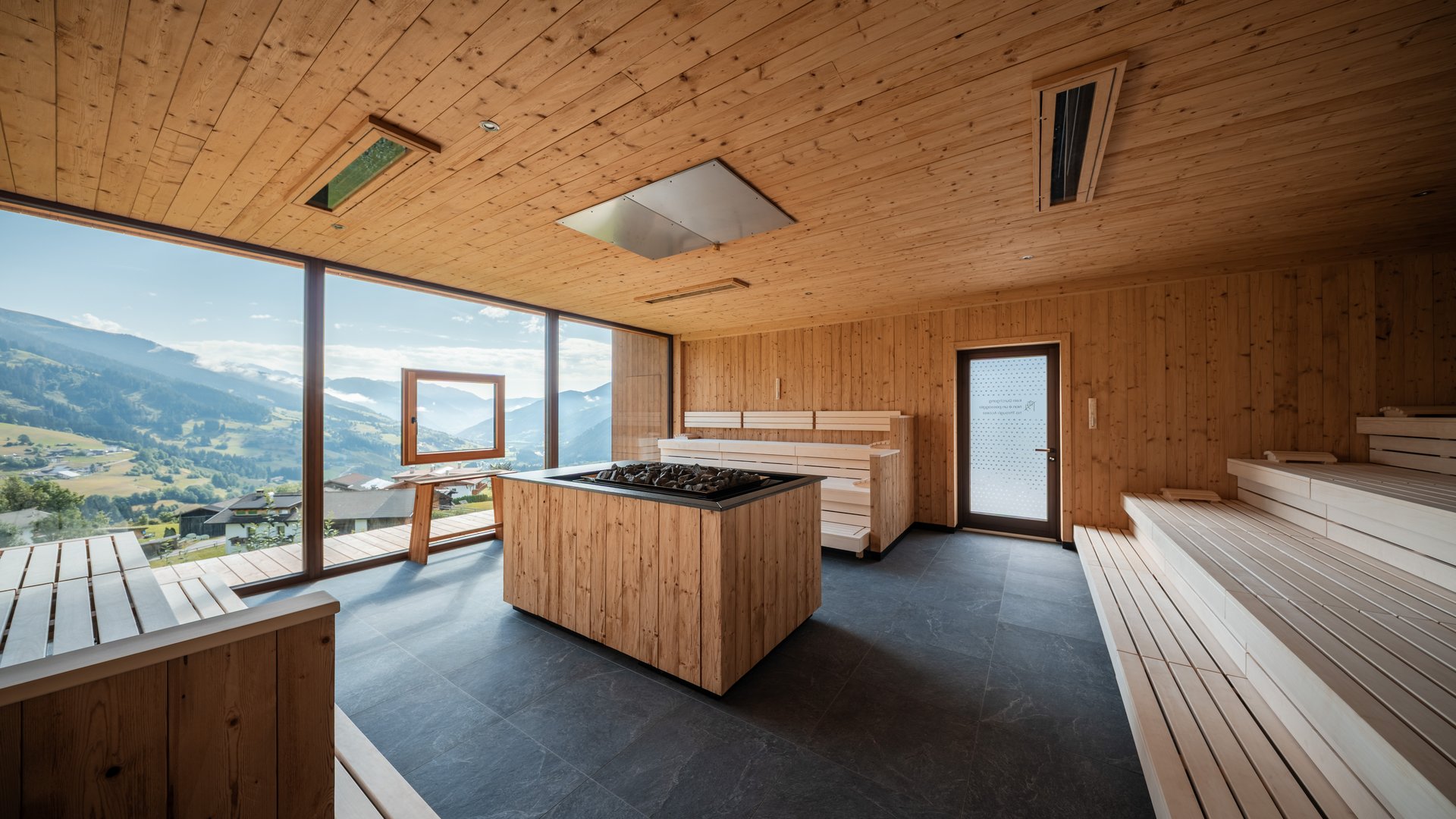 Wellness im Erlebnishotel Gassenhof Heller Holzsaunaraum mit Panoramafenstern und Bergblick