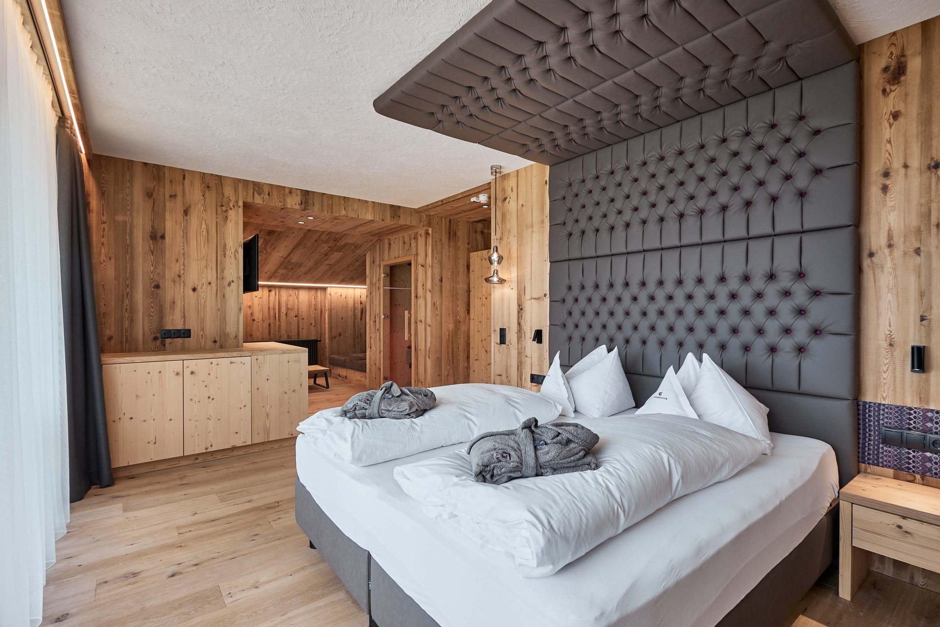 Urlaub anfragen Moderne Holzzimmer mit großem Bett und grauem gepolstertem Kopfteil