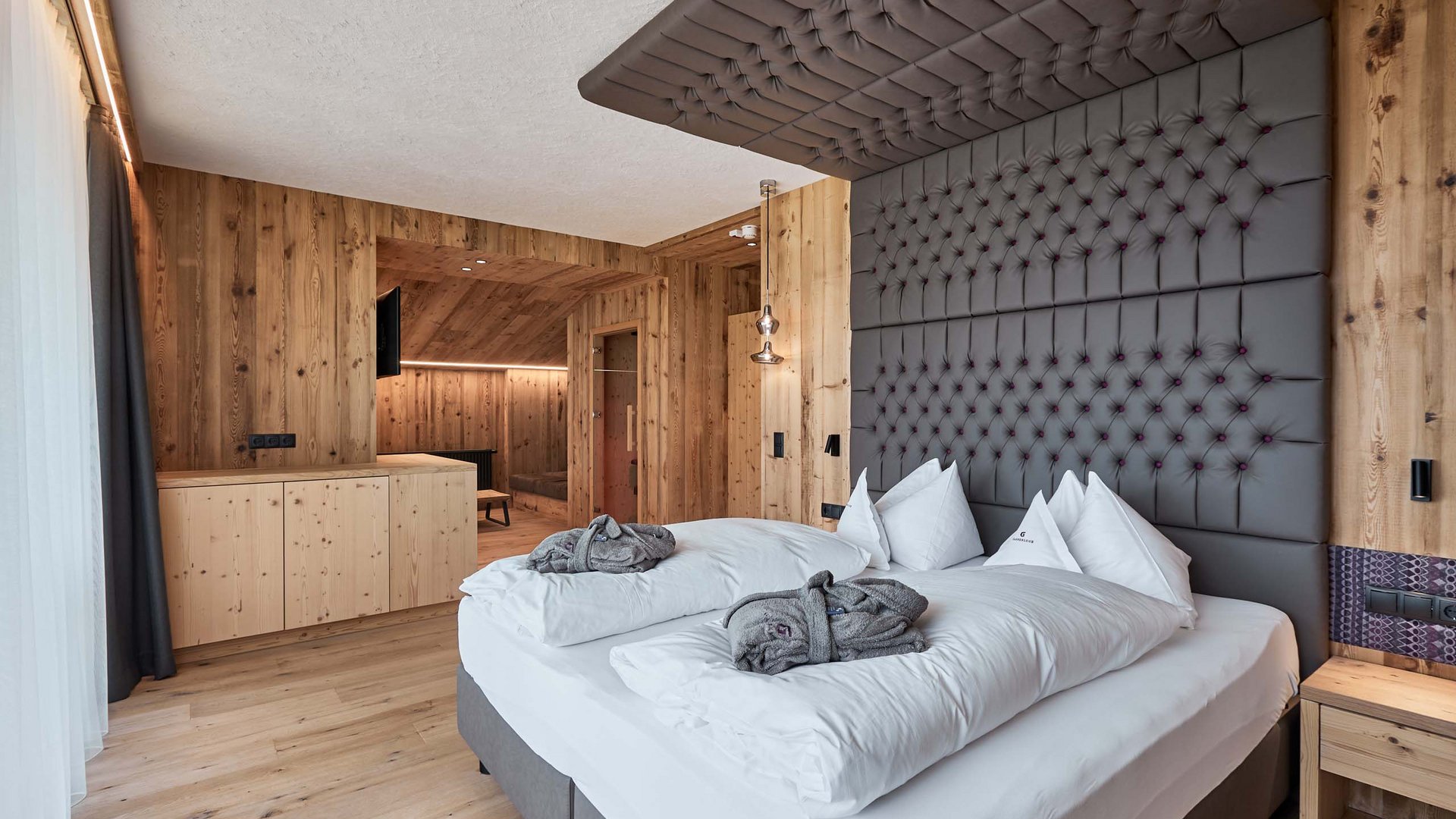 Der Erlebnisort Gassenhof Moderne Holzzimmer mit großem Bett und grauem gepolstertem Kopfteil