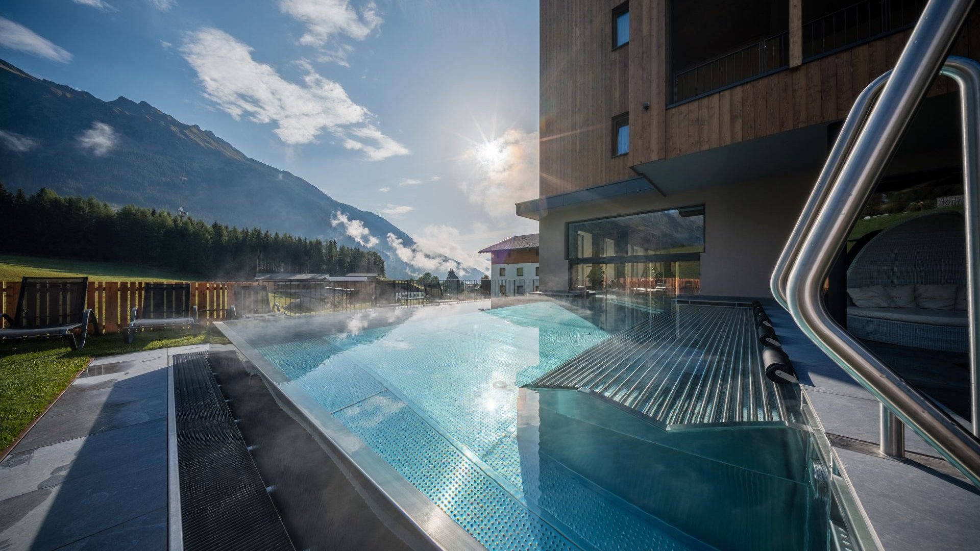 Gassenbadl: l’area wellness per famiglie Piscina esterna riscaldata con vista sulle montagne accanto a un edificio moderno
