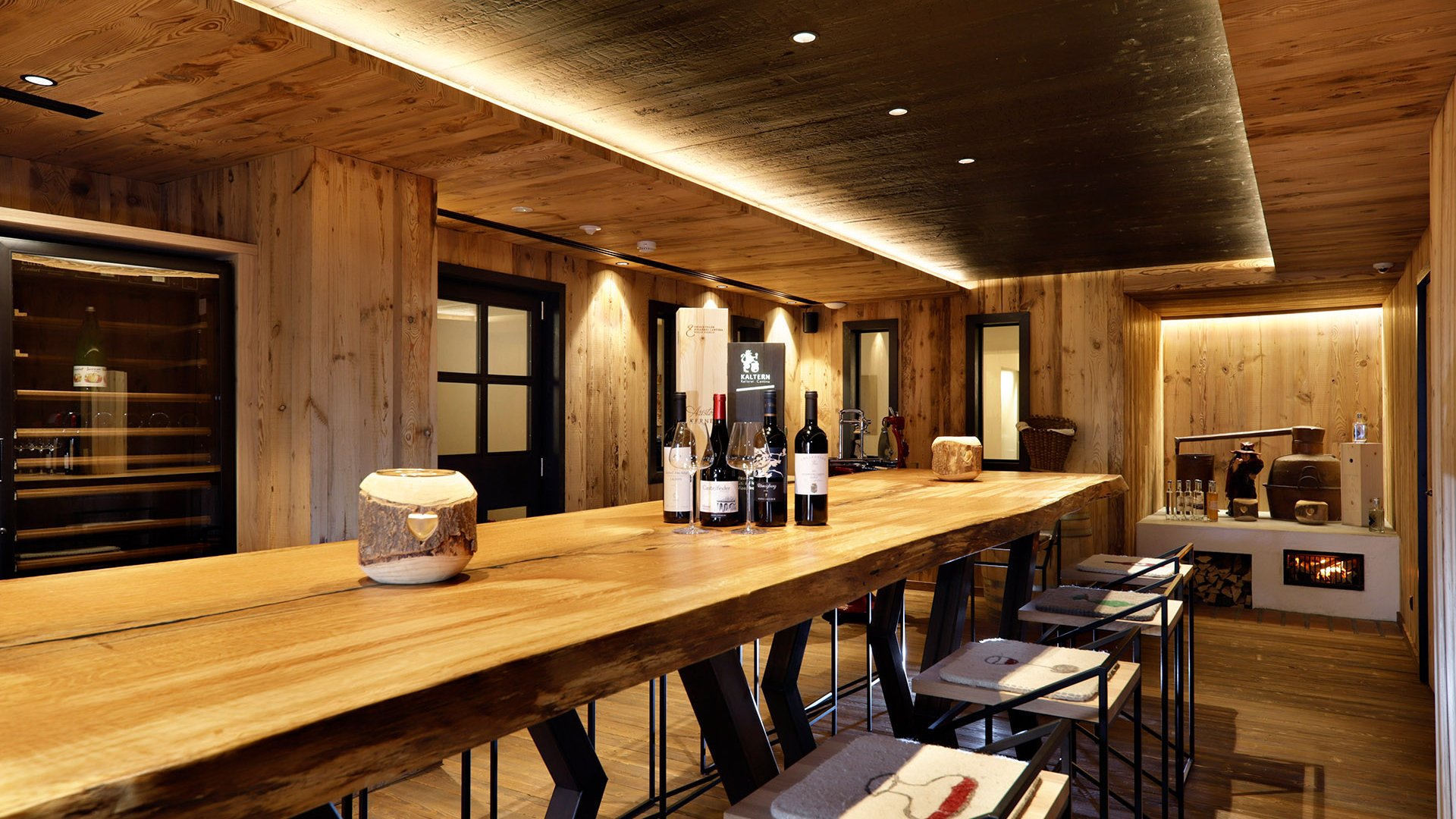 Vini Bar in legno con bottiglie di vino e sedie in una stanza rustica