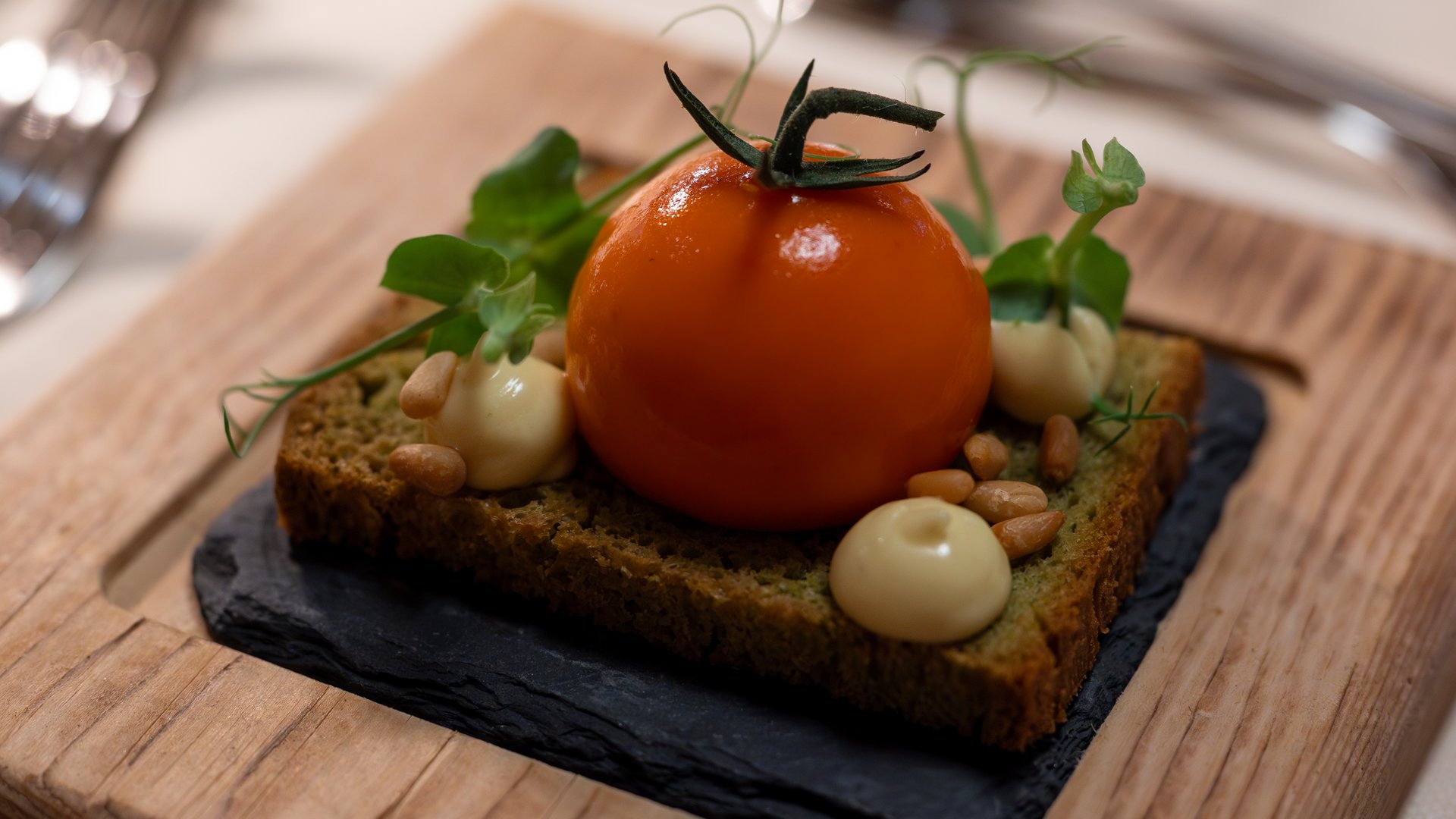 Sapori Pane di piselli con pomodoro, maionese, pinoli e erbe su ardesia