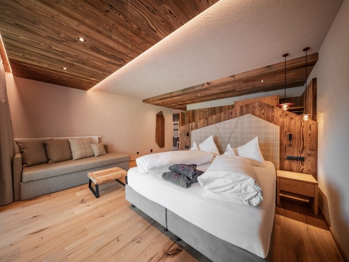 Neu bei uns im Gassenhof Modernes Schlafzimmer mit Doppelbett, Sofa, Holzelementen und warmem Licht