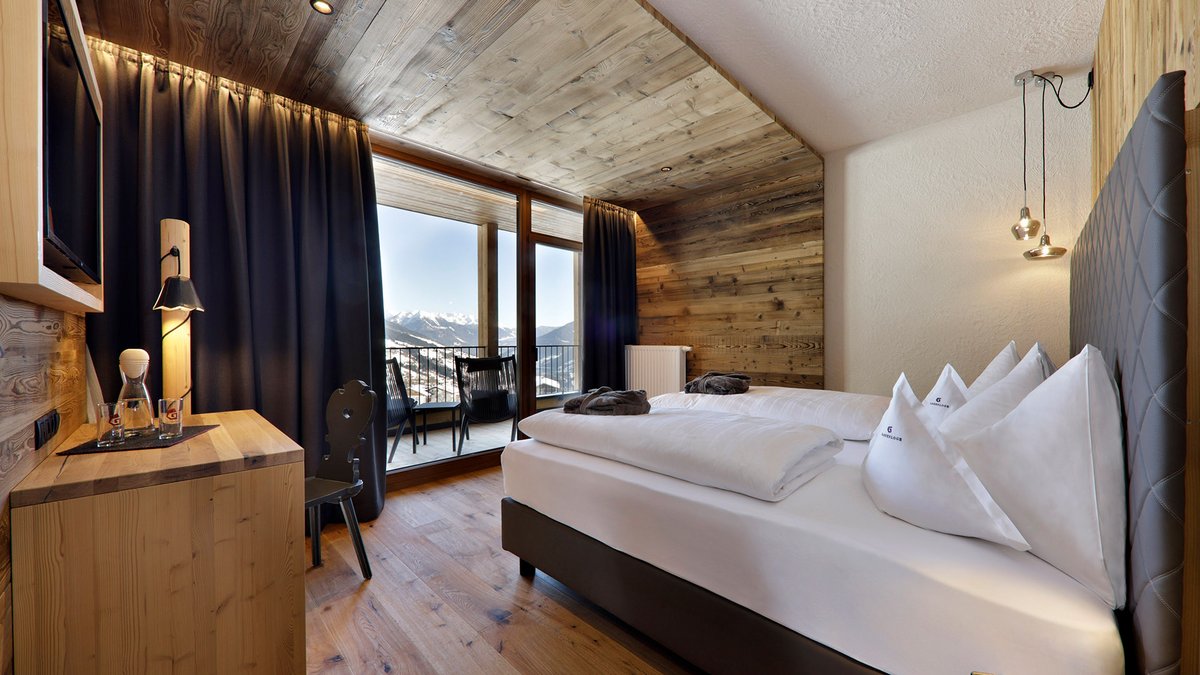 Familienurlaub im Gassenhof Modernes Hotelzimmer mit Holzwänden, Doppelbett und Bergblick
