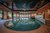 Galleria immagini Elegante piscina interna con area relax, soffitto in legno e scala a chiocciola