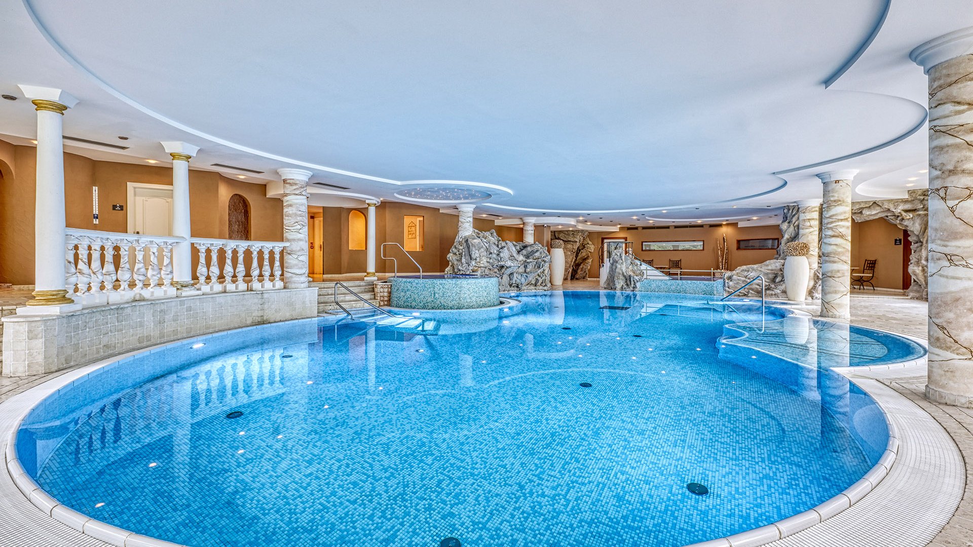 Luxury indoor pool with mosaic tiles and decorative columns