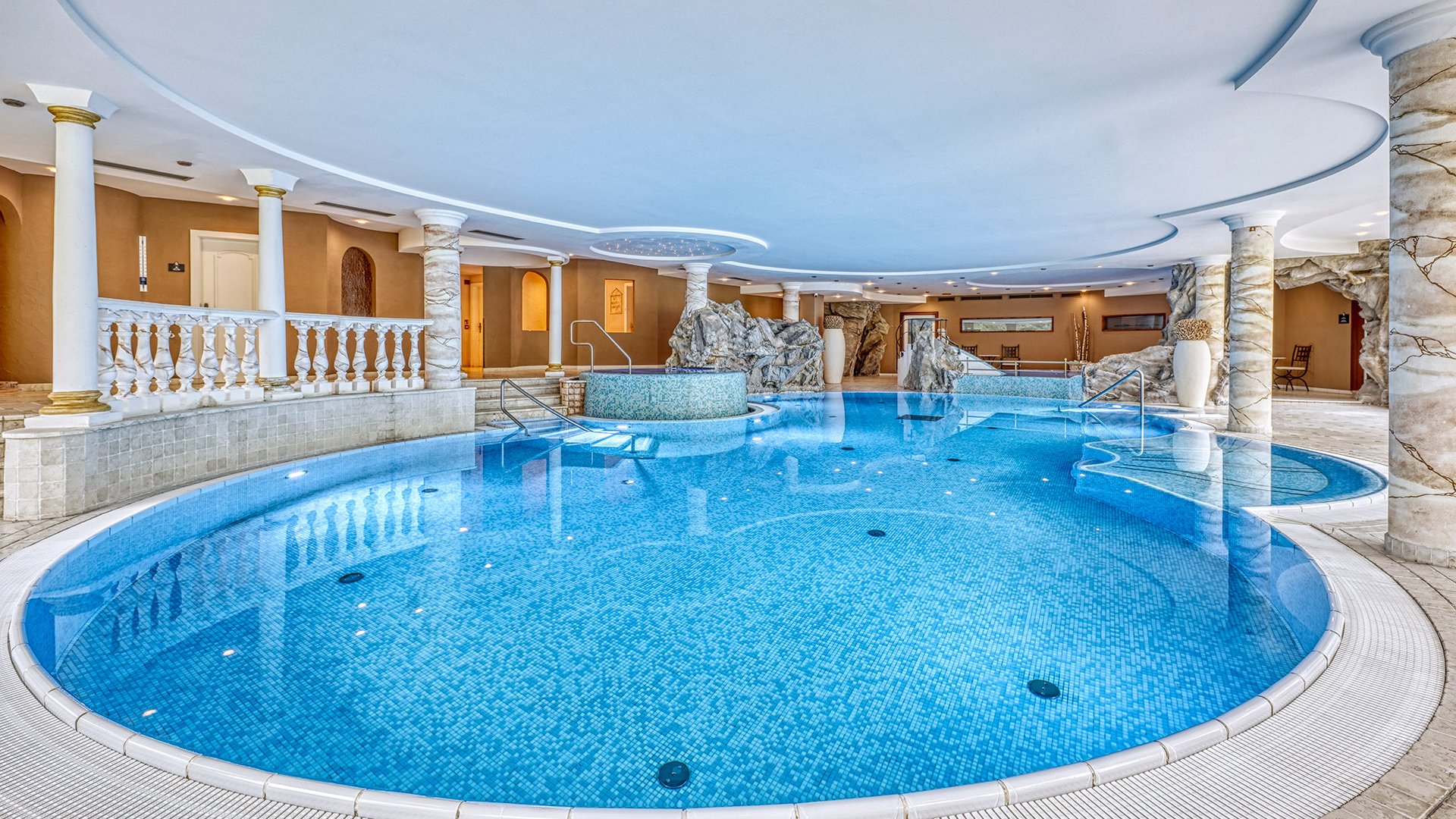 Der Erlebnisort Gassenhof Luxuriöses Hallenbad mit Mosaikfliesen und dekorativen Säulen
