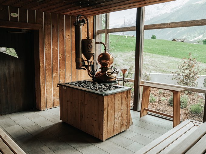 Das Wellnessbereich für Erwachsene Saunaraum mit Holzwänden, Ofen und großem Fenster mit Bergblick