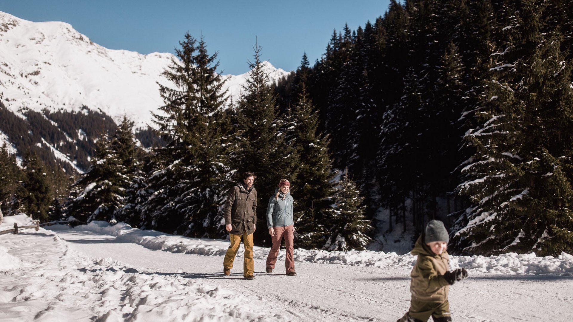 Familienurlaub im Gassenhof Zwei Erwachsene und ein Kind wandern durch eine verschneite Berglandschaft