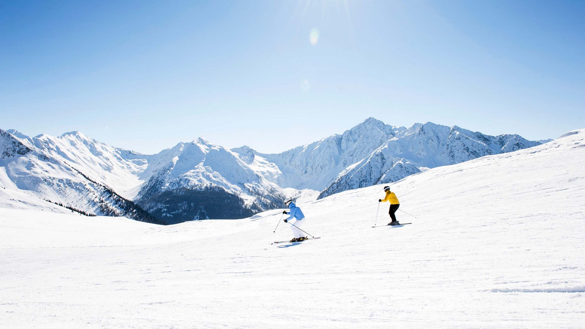 Inclusive services Two skiers on snowy slope with mountains under clear sky