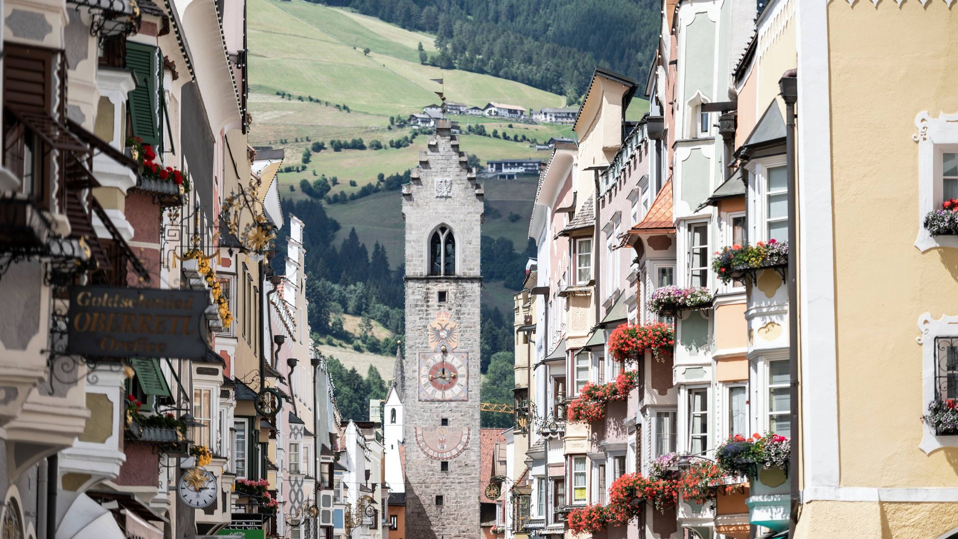 Urlaub bei Sterzing Blick auf die Altstadtstraße mit einem historischen Uhrturm und bunten Häusern