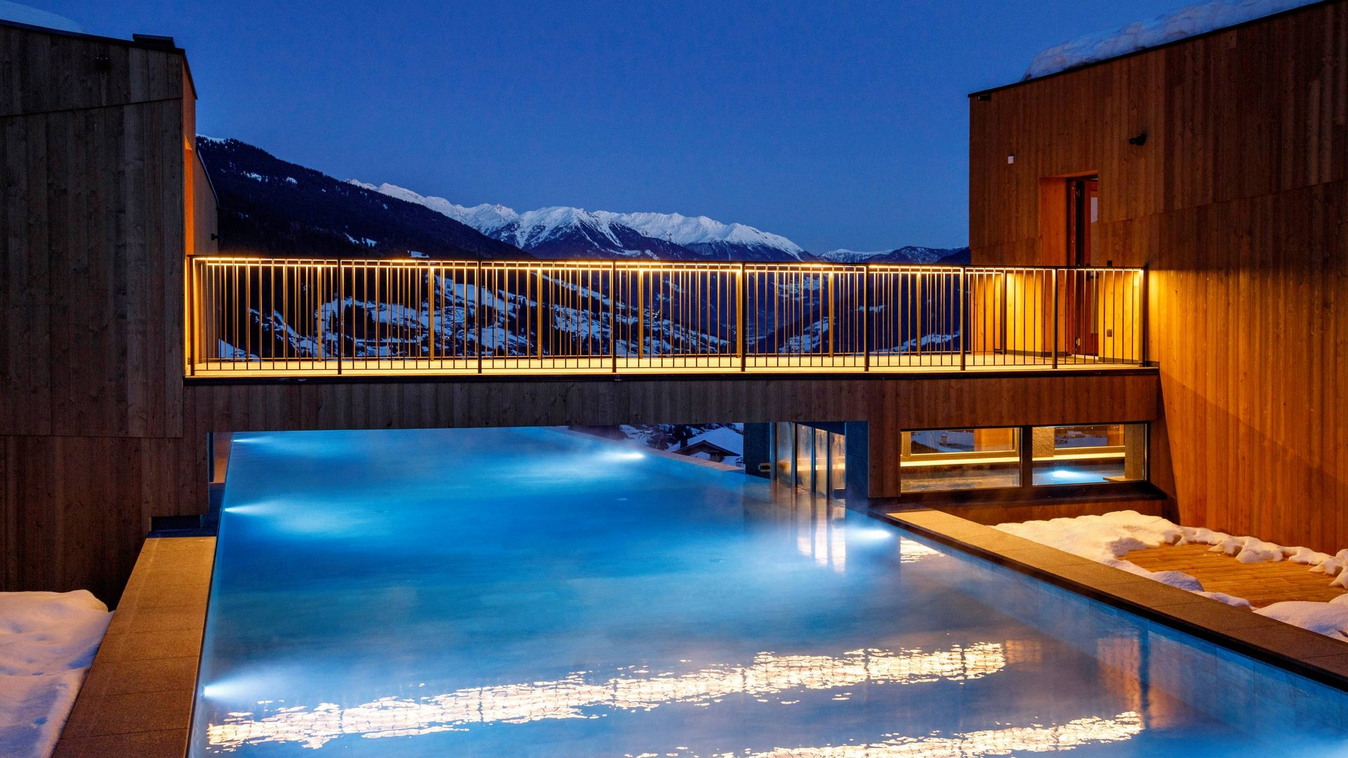 Die Wasserwelt Beleuchteter Außenpool bei Nacht mit Bergblick und Schnee