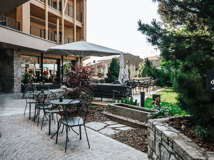 A place of experiences Hotel outdoor area with tables, chairs, and a large umbrella