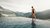 Frau im Badeanzug am Rand eines Infinity-Pools mit Bergblick