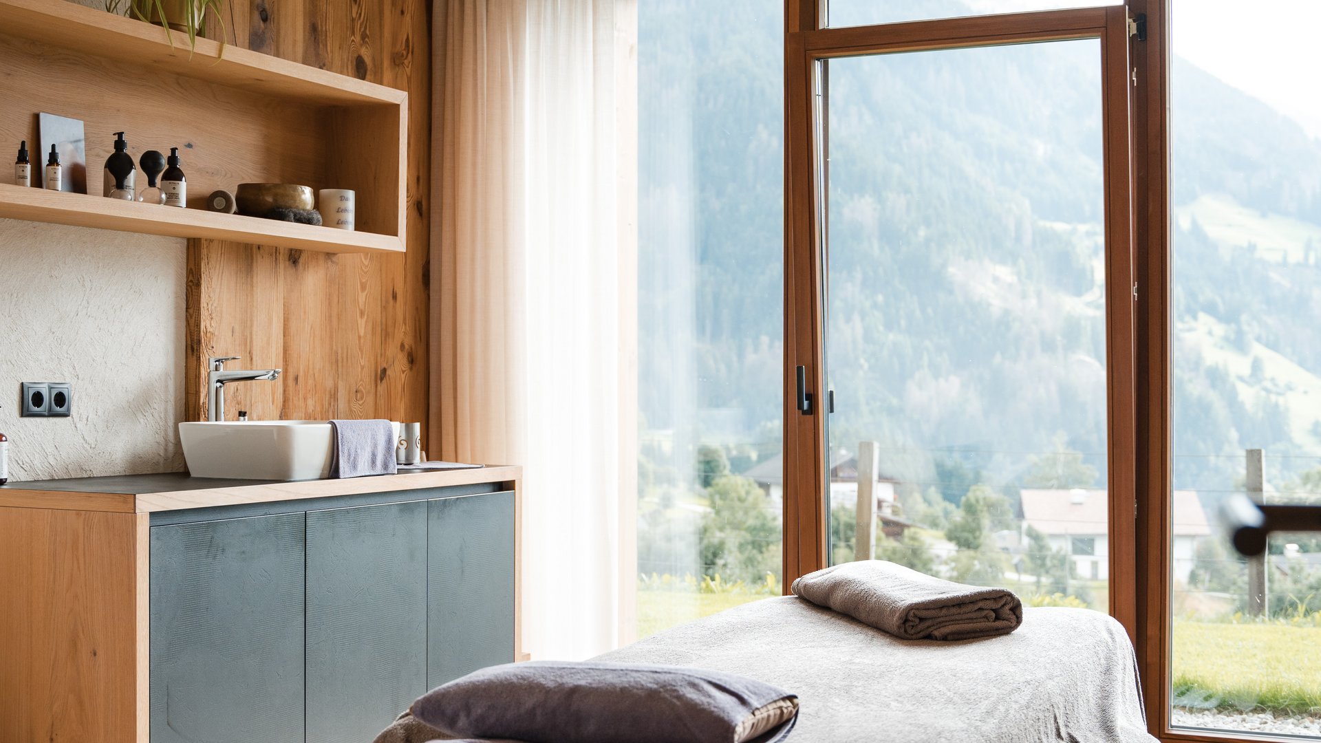Logen Spa Sala massaggi luminosa con lettino e grande finestra con vista sulla montagna