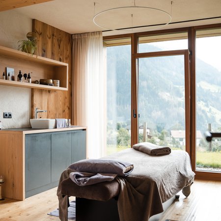 Das Logen-Spa Helles Massageraum mit Liege und großem Fenster mit Bergblick