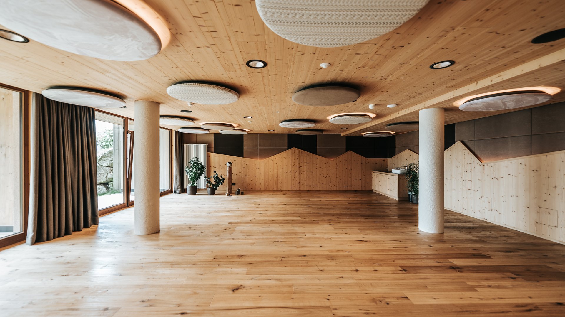 Fitness und Yoga Großer heller Raum mit Holzboden und runden Deckenleuchten