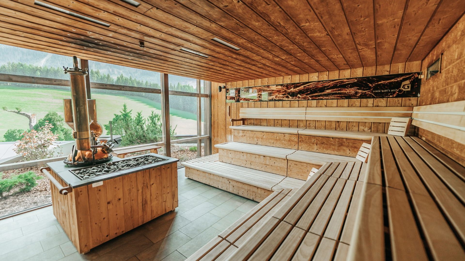 Day Spa Holzsauna mit mehreren Sitzbänken und Ofen vor großen Fenstern