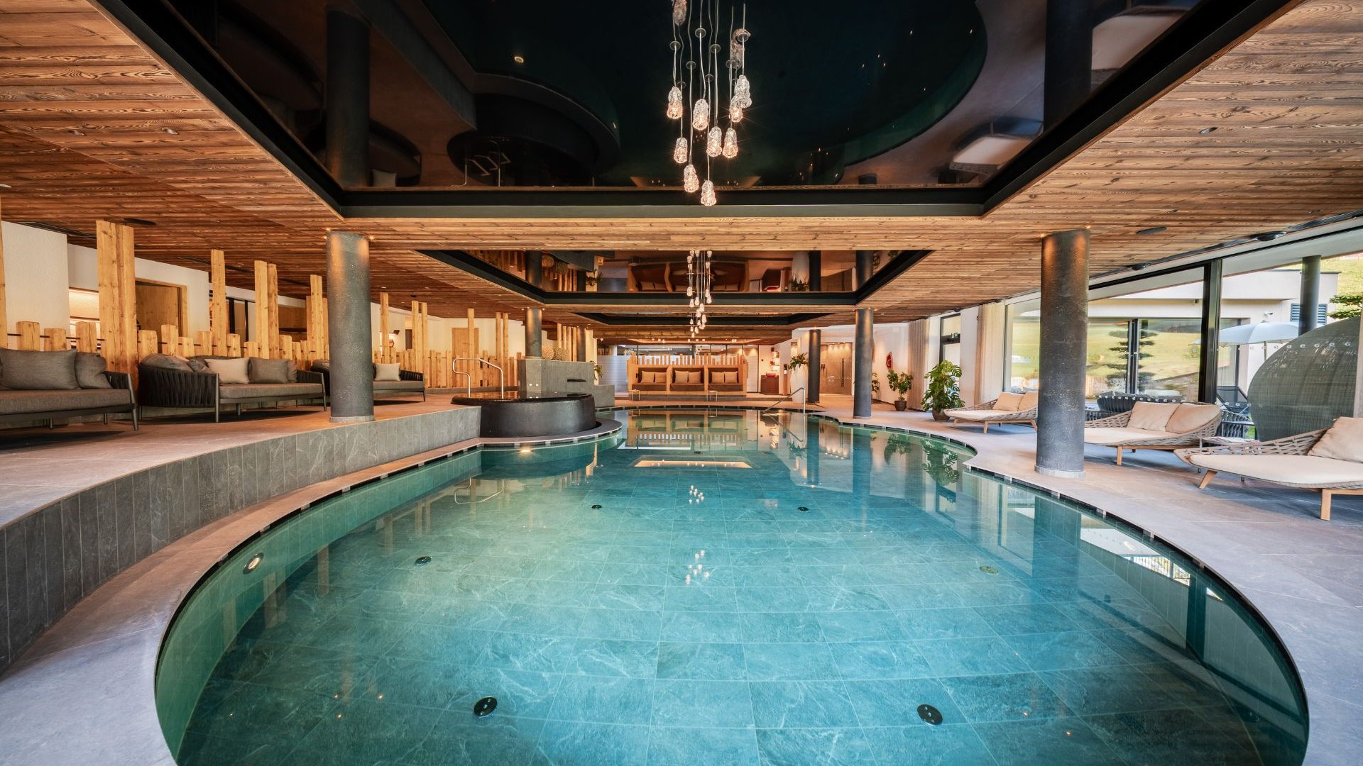 Gassenbadl: l’area wellness per famiglie Elegante piscina interna con aree relax, lettini e soffitto in legno