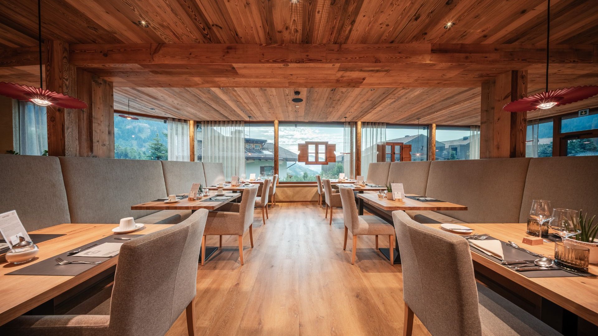 Neu bei uns im Gassenhof Holzrestaurant mit gedeckten Tischen und Bergblick durch große Fenster