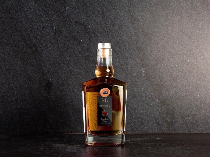 Der beste Whiskey der Alpen Flasche Becher Whisky auf dunkelgrauem Steinuntergrund