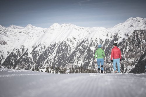 Vacanze in Alto Adige Due persone camminano su pista innevata con vista sulle montagne innevate