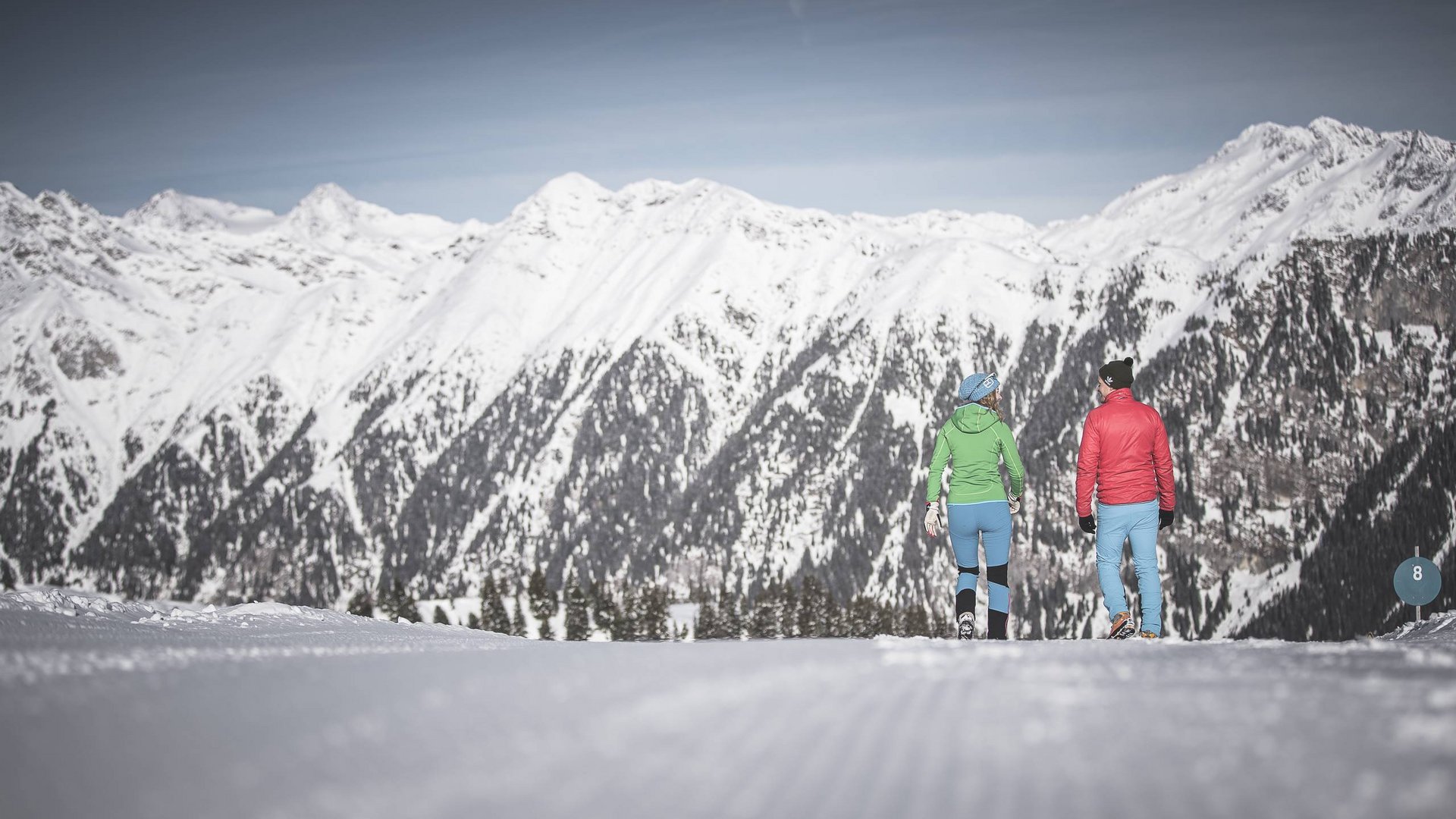 Der Erlebnisort Gassenhof Zwei Personen wandern auf verschneiter Piste mit Blick auf schneebedeckte Berge