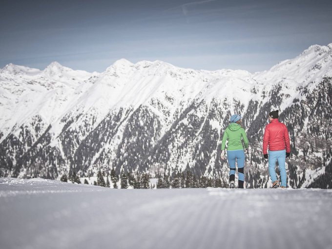 Winterwandern Zwei Personen wandern auf verschneiter Piste mit Blick auf schneebedeckte Berge