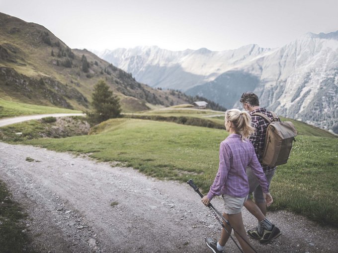 Escursioni in estate Due escursionisti camminano su un sentiero di montagna con le Alpi sullo sfondo