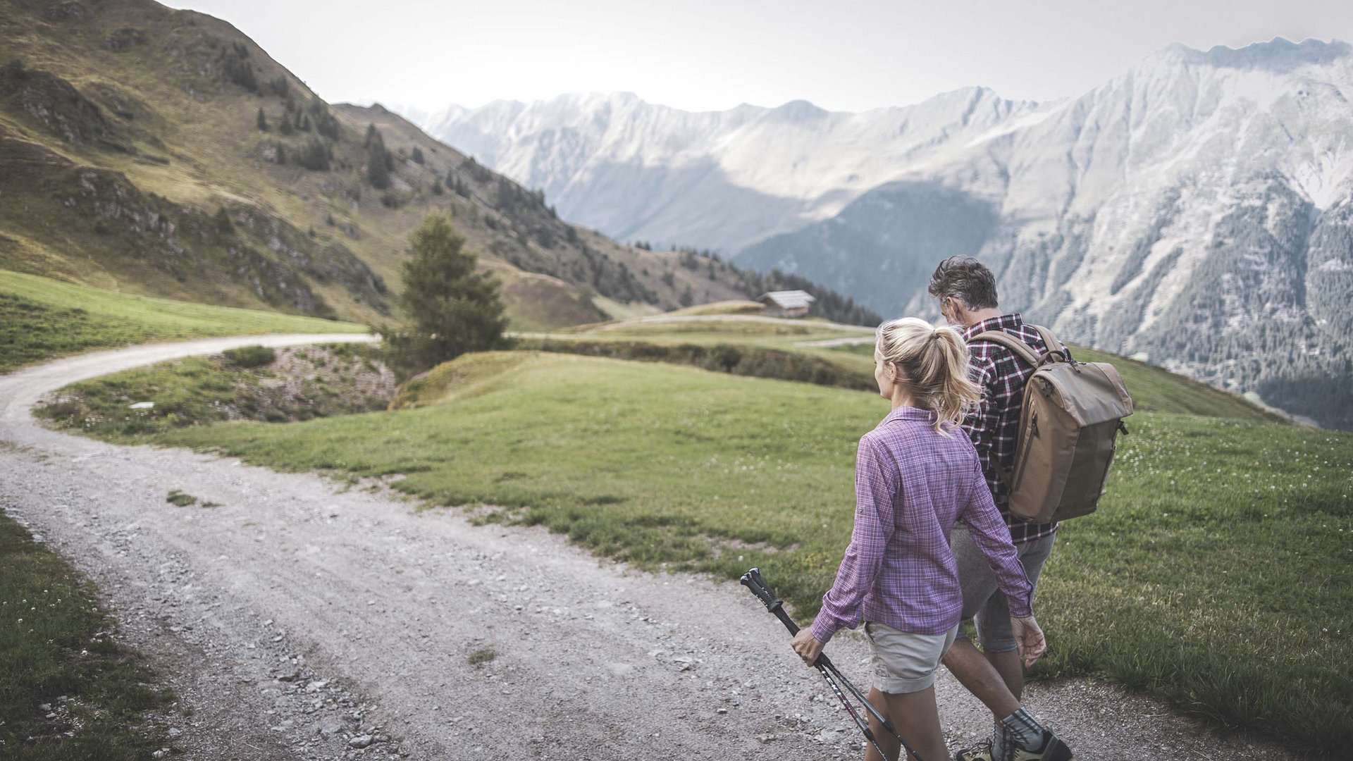 Der Erlebnisort Gassenhof Zwei Wanderer gehen auf einem Bergpfad mit Alpen im Hintergrund