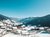Schneebedecktes Dorf in einem Tal mit Bergen und klarem blauem Himmel