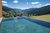 Infinity-Pool mit Bergblick und Häusern im Tal bei sonnigem Wetter