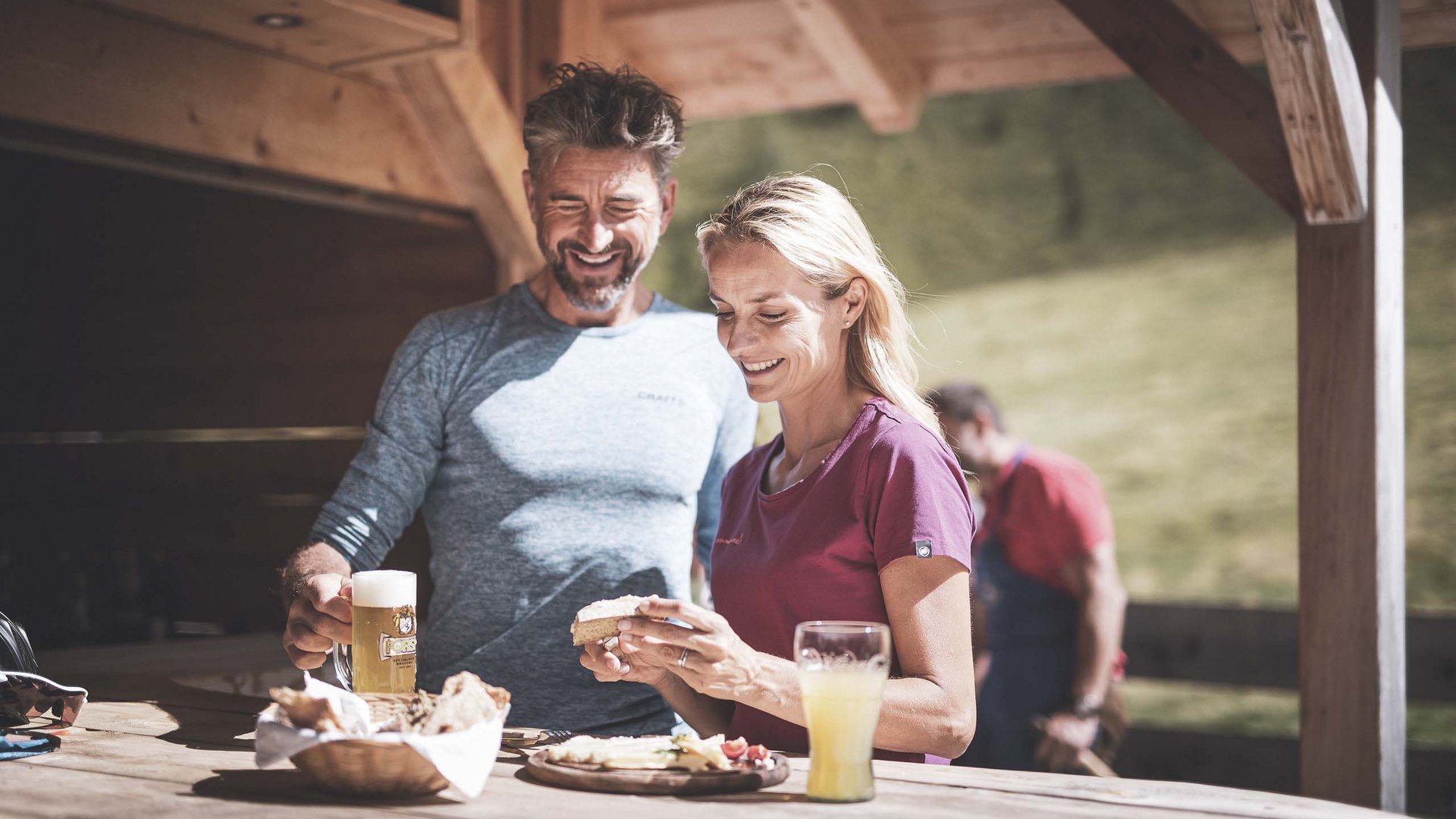 Vitalpina hotel in Alto Adige Coppia che gusta snack e bevande su un tavolo di legno all'aperto