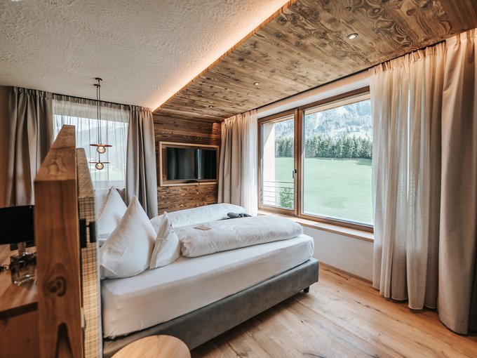 New at Gassenhof Cozy hotel room with wooden accents and large window overlooking mountain view