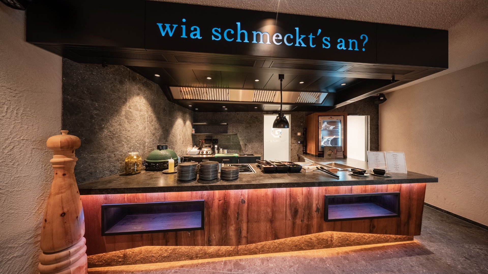 The Gassenhof gourmet cuisine Buffet with cooking area, dishes and refrigerator beneath the Wia schmeckt’s an? sign