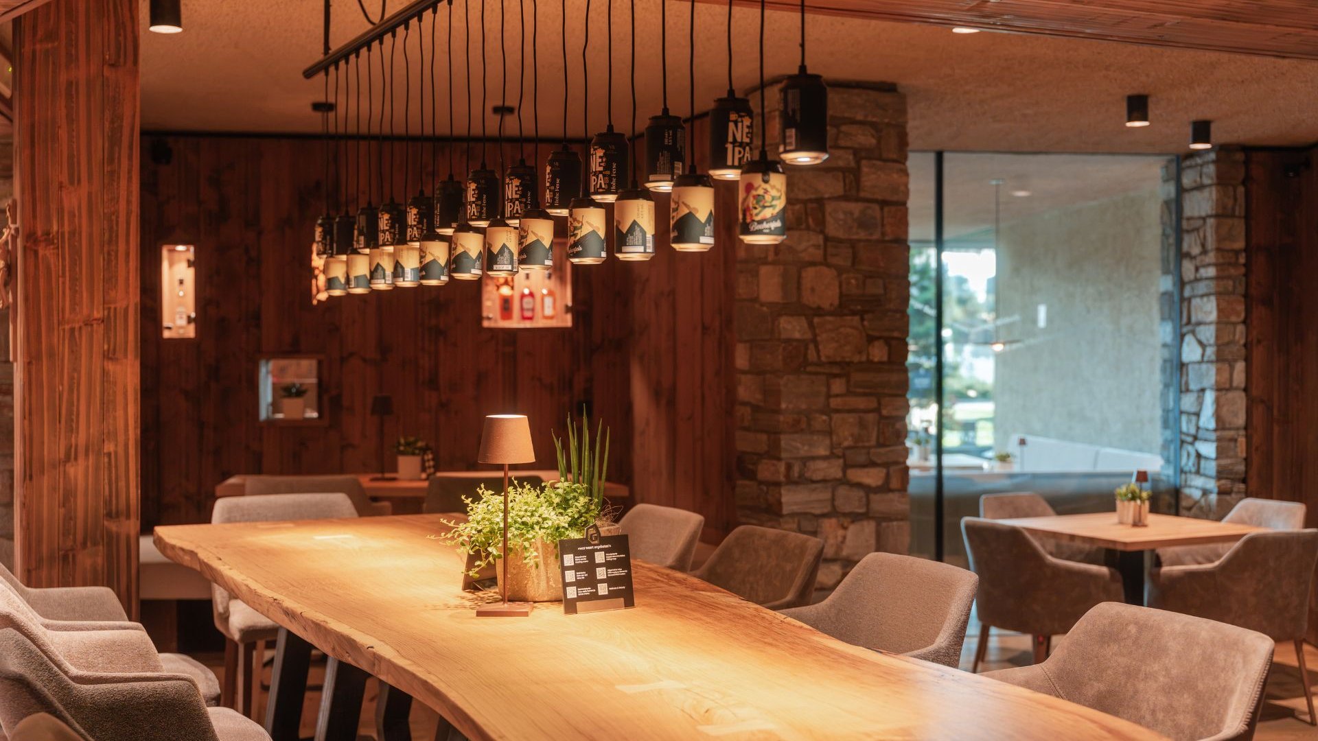 Sapori Sala ristorante rustica con lungo tavolo in legno, lampade sospese e colonna in pietra
