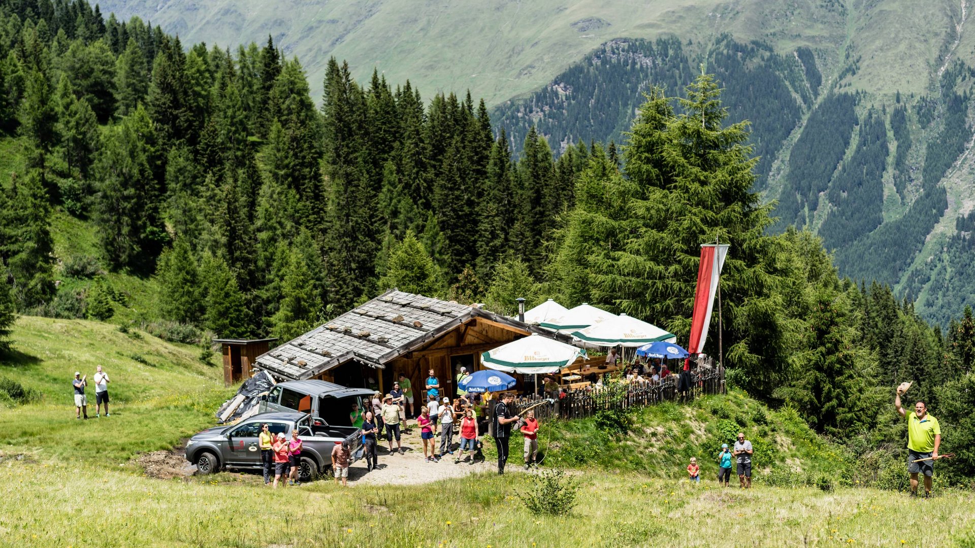 Summer hiking People gathered in front of a mountain hut in the Alps on a sunny day