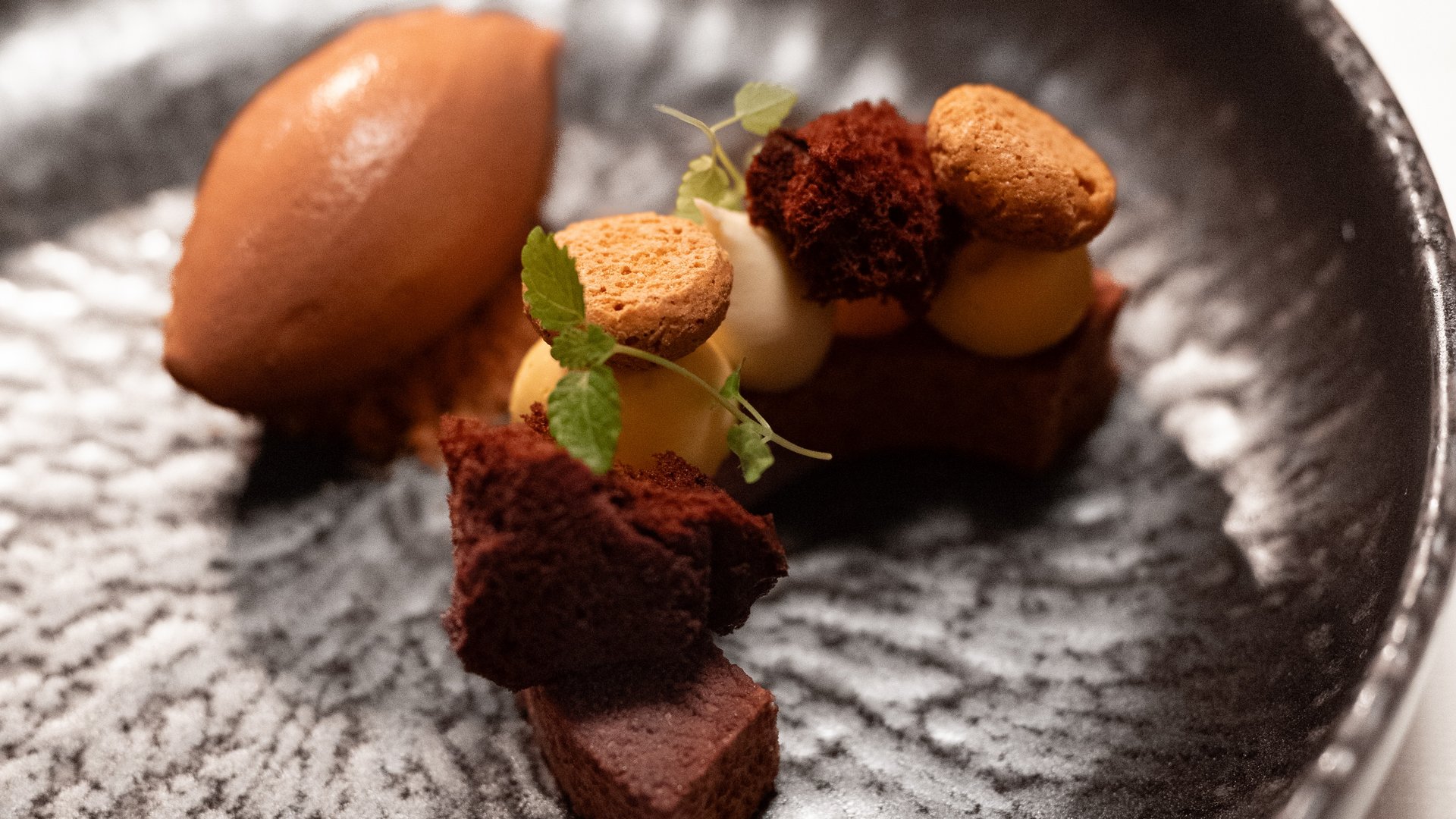 Sapori Dessert artistico con gelato al cioccolato e piccoli pezzi di torta su piatto nero