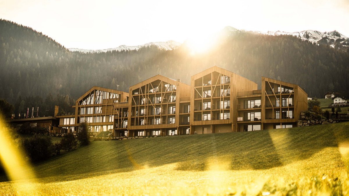The best spot in the Ridnauntal valley Modern wooden building in front of forested mountains in sunlight
