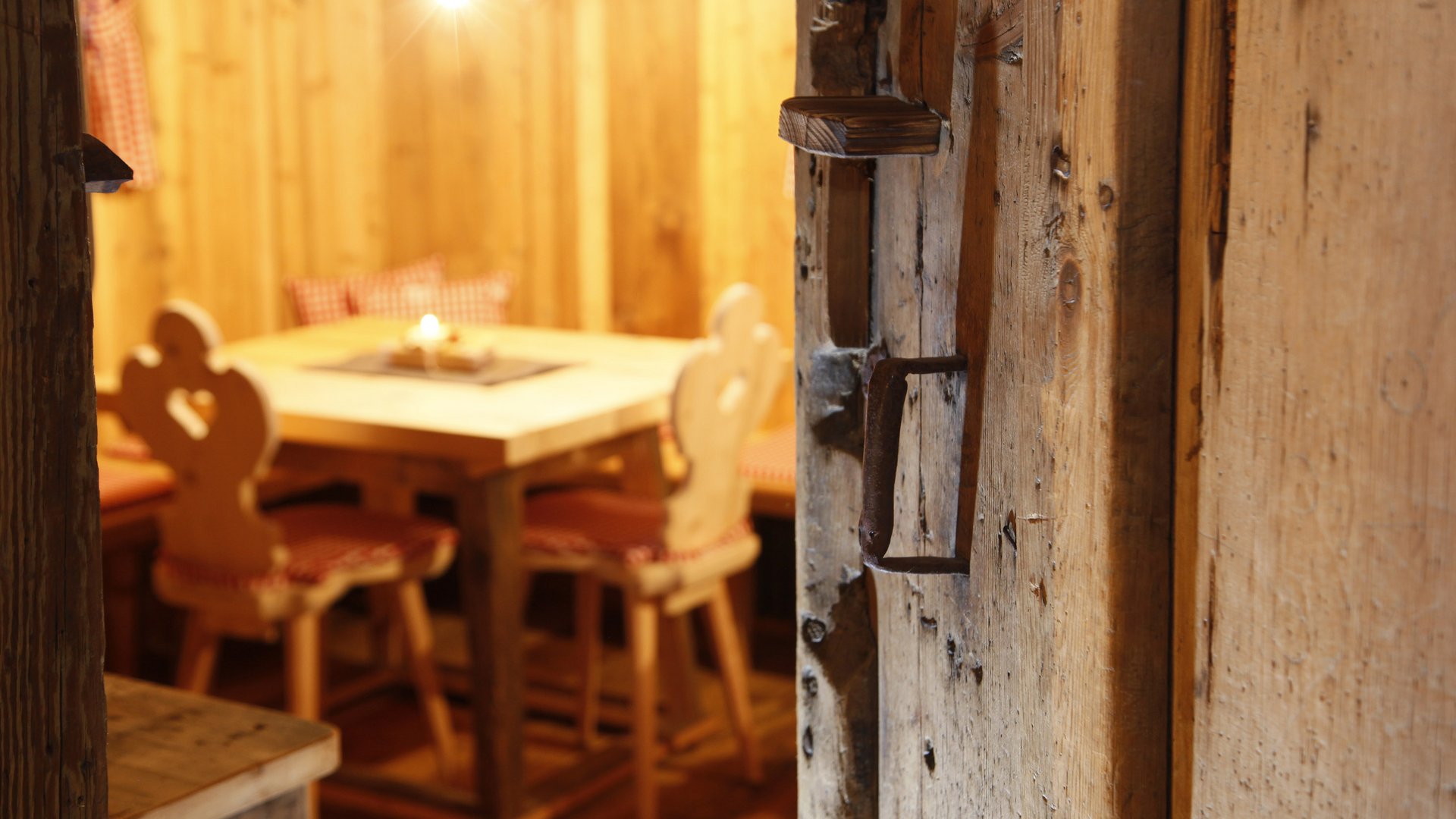 The historical Chalet Gratznhäusl View through an old wooden door into a cozy wooden room with table and chairs