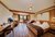 Gemütliches Hotelzimmer mit Holzmöbeln, Bett, Sofa und Balkon mit Aussicht