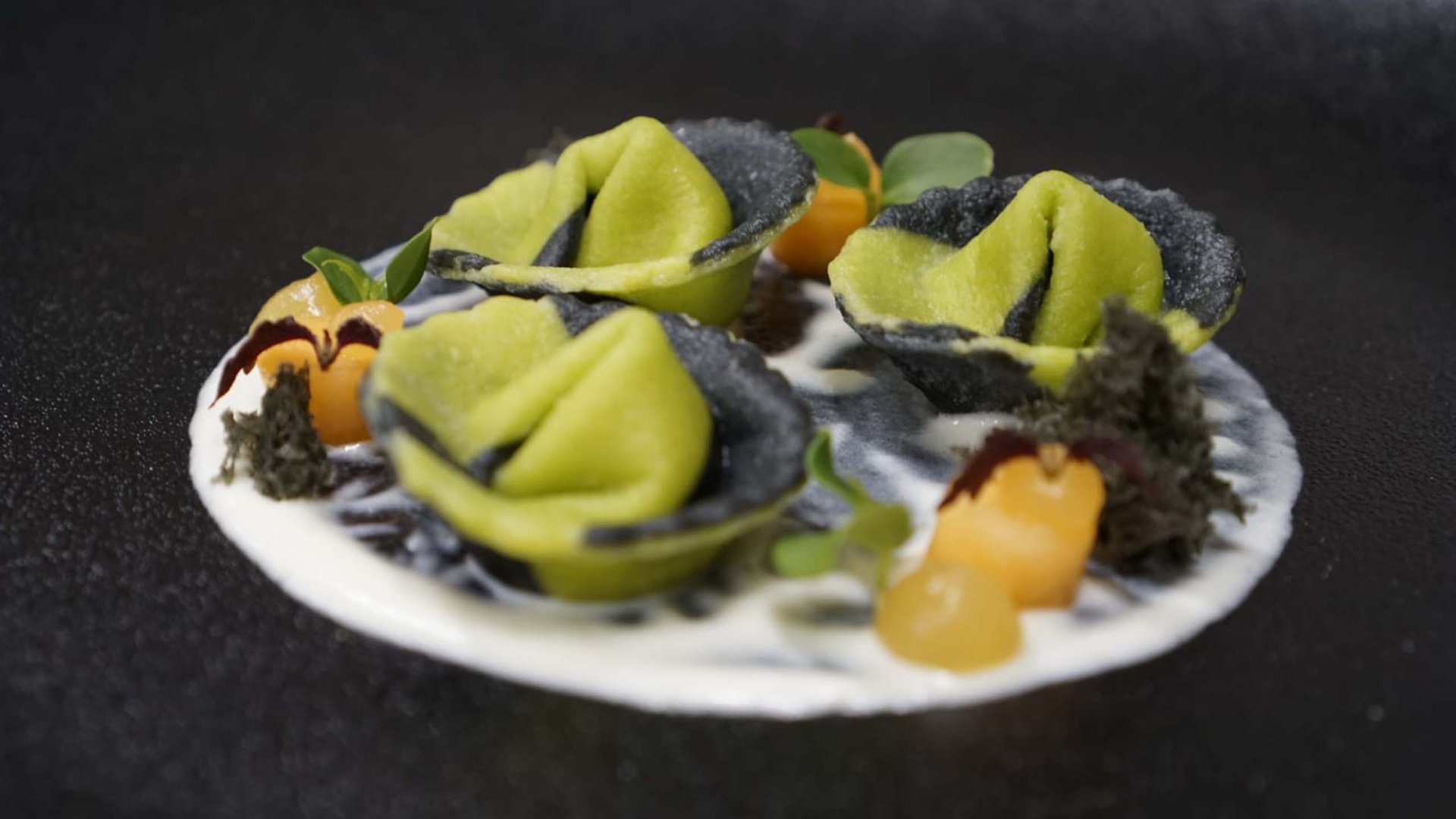 Sapori Pasta ripiena verde e nera elegantemente disposta su salsa bianca